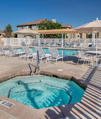 A pool with a hot tub and sun loungers.