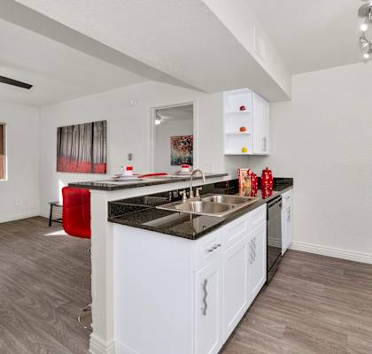 A kitchen with white cabinets and a black countertop at Urban WalkApartments on 6th Avenue, Phoenix 85016