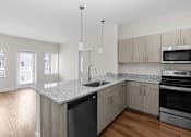 Thumbnail 3 of 8 - A kitchen with a granite countertop and stainless steel appliances.