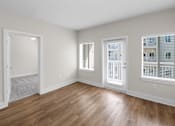 Thumbnail 4 of 8 - A room with wooden floors and three windows.