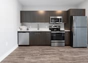 Thumbnail 8 of 9 - A modern kitchen with dark wood cabinets and stainless steel appliances.