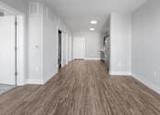 Thumbnail 6 of 9 - A long hallway with wood flooring and white walls.