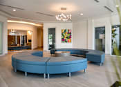 Thumbnail 6 of 6 - A modern living room with a large blue sofa and a painting on the wall.