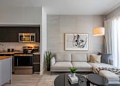 Thumbnail 24 of 31 - A modern living room with a grey sofa and a black coffee table.