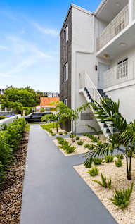 A white building with a concrete walkway in front of it.