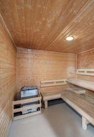 A wooden sauna room with benches and a table.