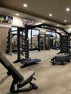 a spacious fitness room with cardio equipment and weights