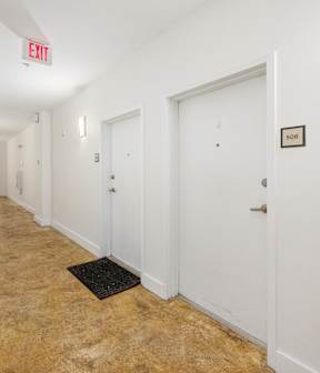A hallway with a red exit sign above the door on the right.
