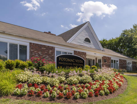the front of the potomac west leasing center with a sign and flowers in front of