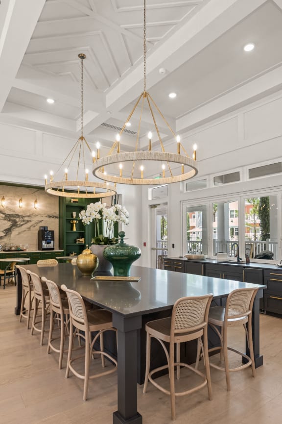 the kitchen has a large island with chairs and a chandelier
