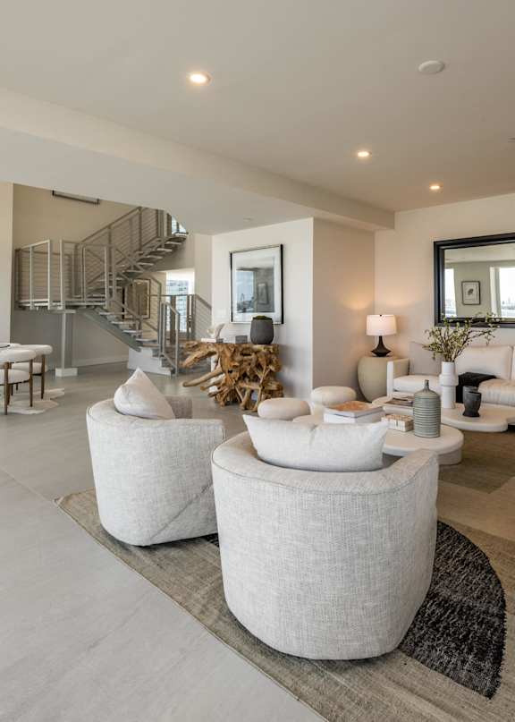 A modern living room with white furniture and a staircase in the background. at The Hamilton, Miami, FL