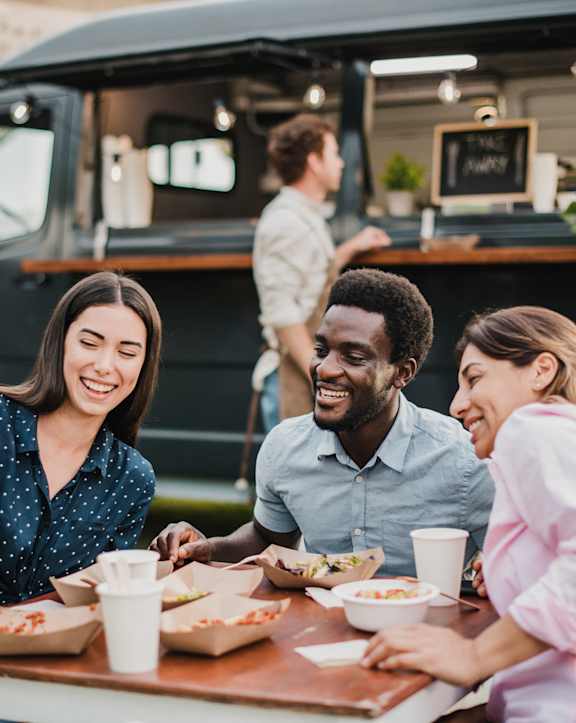 group of people sitting at a table at a food truck