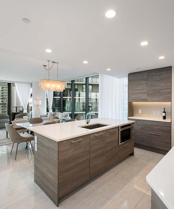 A modern kitchen with a white countertop and wooden cabinets.