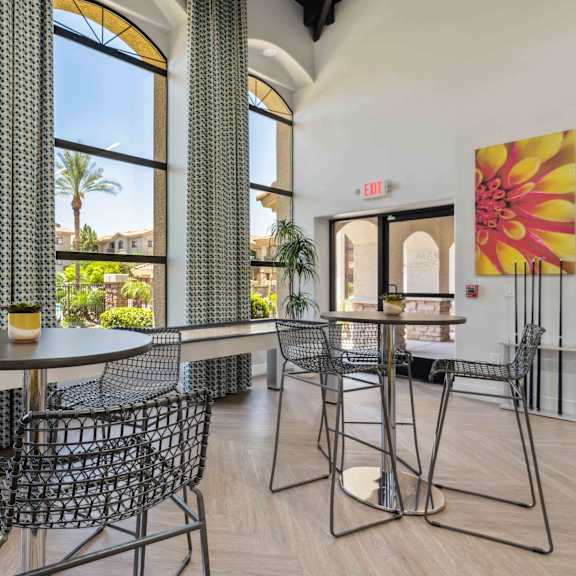 A dining room with a table and chairs and a painting on the wall.