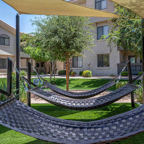 A hammock is suspended between two poles in a grassy area.