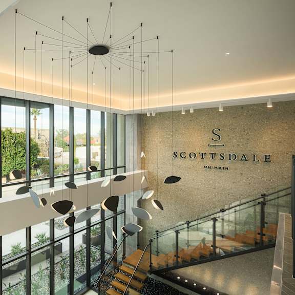 A modern interior of a building with a glass staircase and a hanging light fixture.