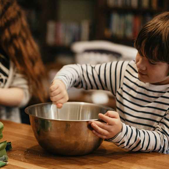 A woman and a child are cooking together in a kitchen.