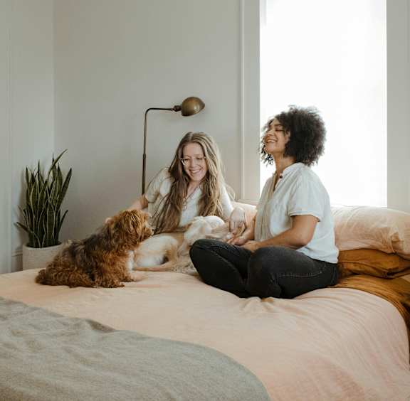 two people sitting on a bed with a dog