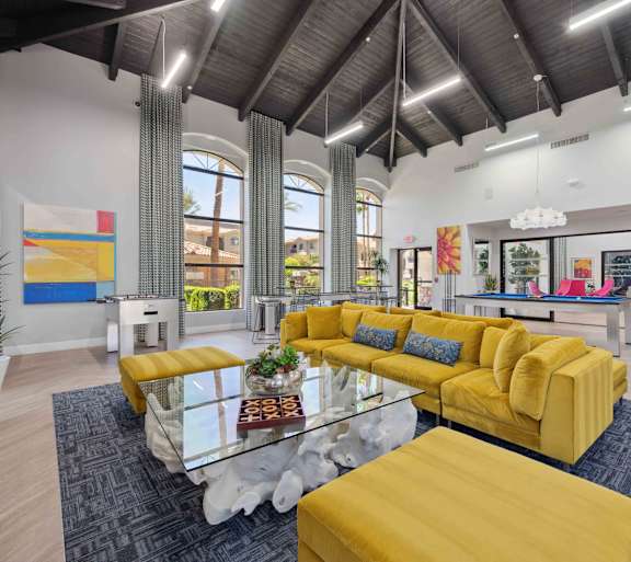 A modern living room with a yellow sofa and glass coffee table.