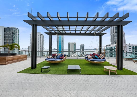 a rooftop lounge area with two hammocks and a view of the city