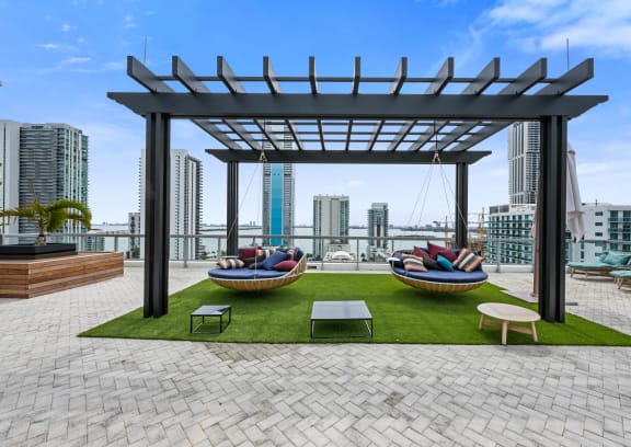an outdoor area with lounge chairs and a hammock with a view of the city