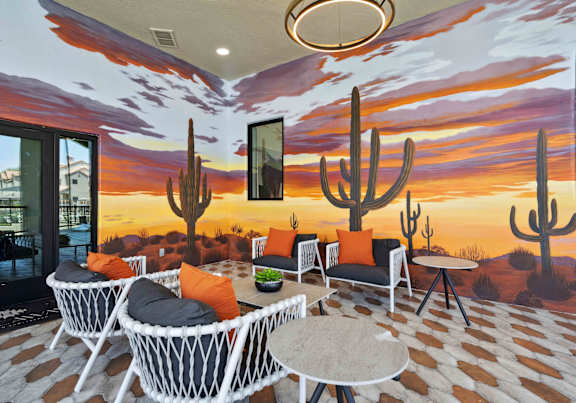 A room with a desert mural on the wall and a table with chairs in front of it.