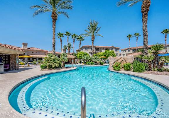 A swimming pool surrounded by palm trees and residential buildings.