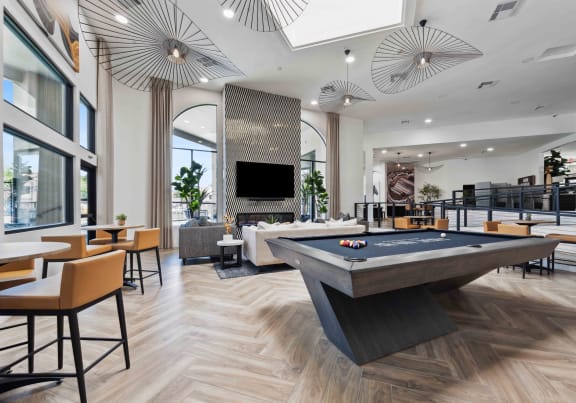 a view of the clubhouse with a pool table in the foreground and tables and chairs in the
