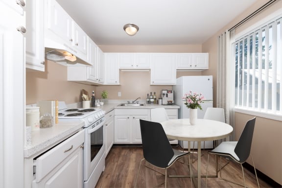 a kitchen with white cabinets and a white table with black chairs
