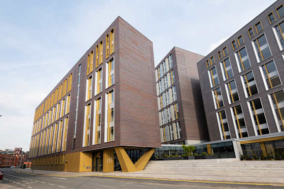 the corner of a building with a street in front of it at The Trilogy Apartments, Manchester, M15 4RU