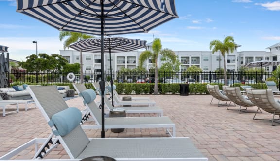 a pool with lounge chairs and umbrellas in front of a building