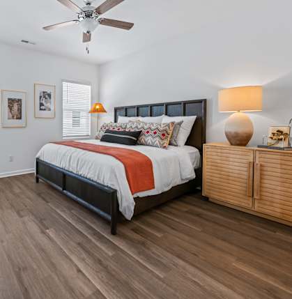 A bedroom with a bed, a dresser, and a ceiling fan.