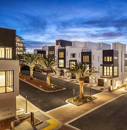 A modern residential area with palm trees and well-lit streets.