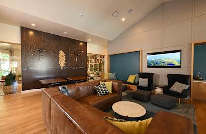 A living room with a brown couch and a television on the wall.