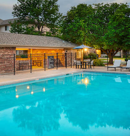 A pool surrounded by a black fence and a building in the background.