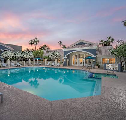 A swimming pool surrounded by lounge chairs and umbrellas.