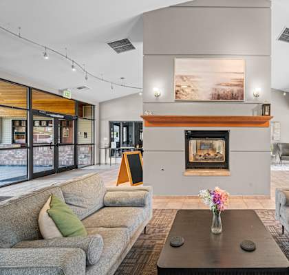 A living room with a fireplace and two grey couches.