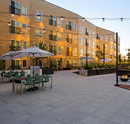 a courtyard with tables and umbrellas in front of an apartment building
