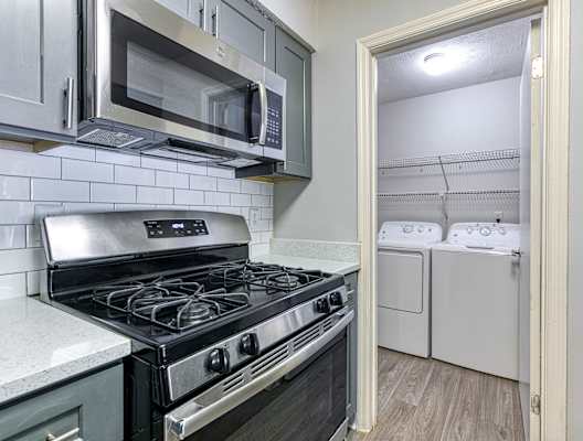 a kitchen with a stove and microwave and a washer and dryer