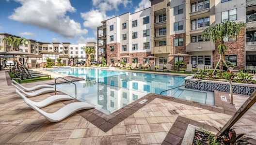 a swimming pool at an apartment building with a pool and lounge chairs at The Haven at Lake Britt Apartments, Winter Garden, FL 34787