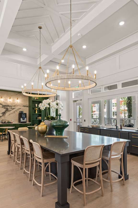 the kitchen has a large island with chairs and a chandelier