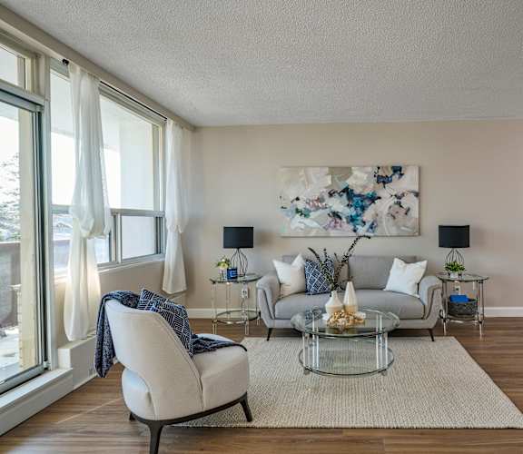 A living room with a white chair, a grey couch, and a glass coffee table.
