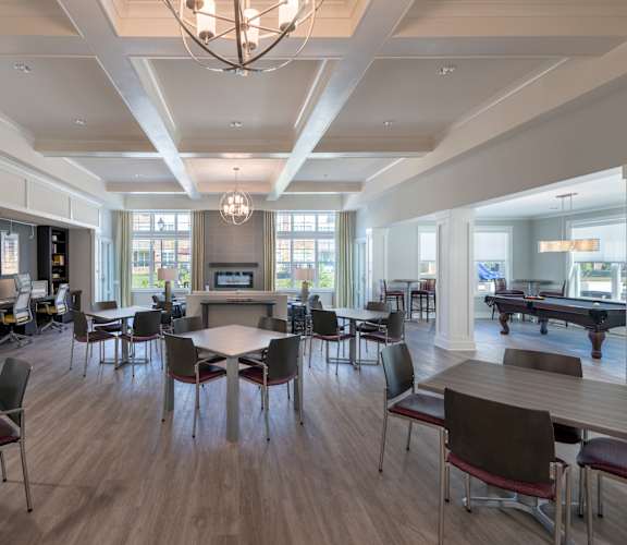 A large room with tables and chairs and a pool table.