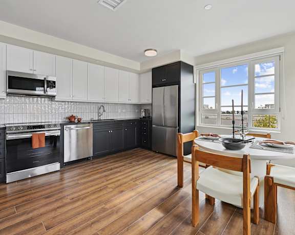 a kitchen with black cabinets and a table and chairs The Baxter in Los Angeles, CA 90028