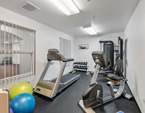 two treadmills and other exercise equipment in a gym with a window