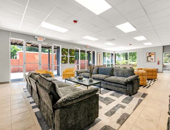 A spacious living room with grey couches and a black and white rug.