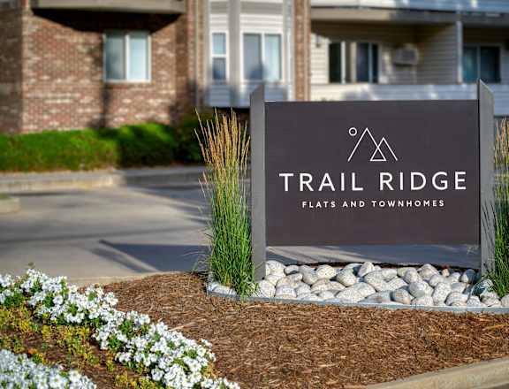 A sign for Trail Ridge Flats and Townhomes is in front of a building.