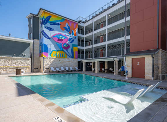 A pool with a white fountain in the middle of it.