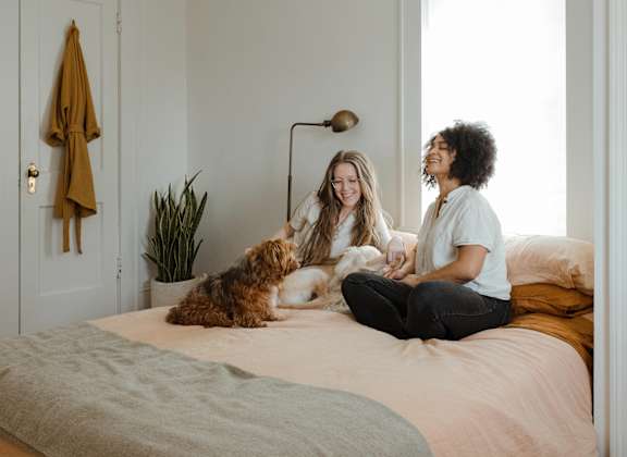 a man and woman sitting on a bed with a dog