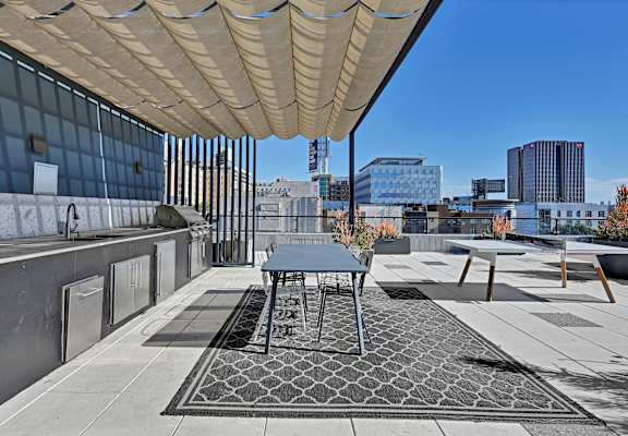 A patio with a table and chairs under a shade structure.